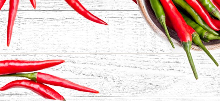Fresh red and green chillies on a whitewashed wooden surface