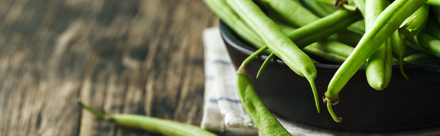 Fresh green beans in a bowl on a rustic table