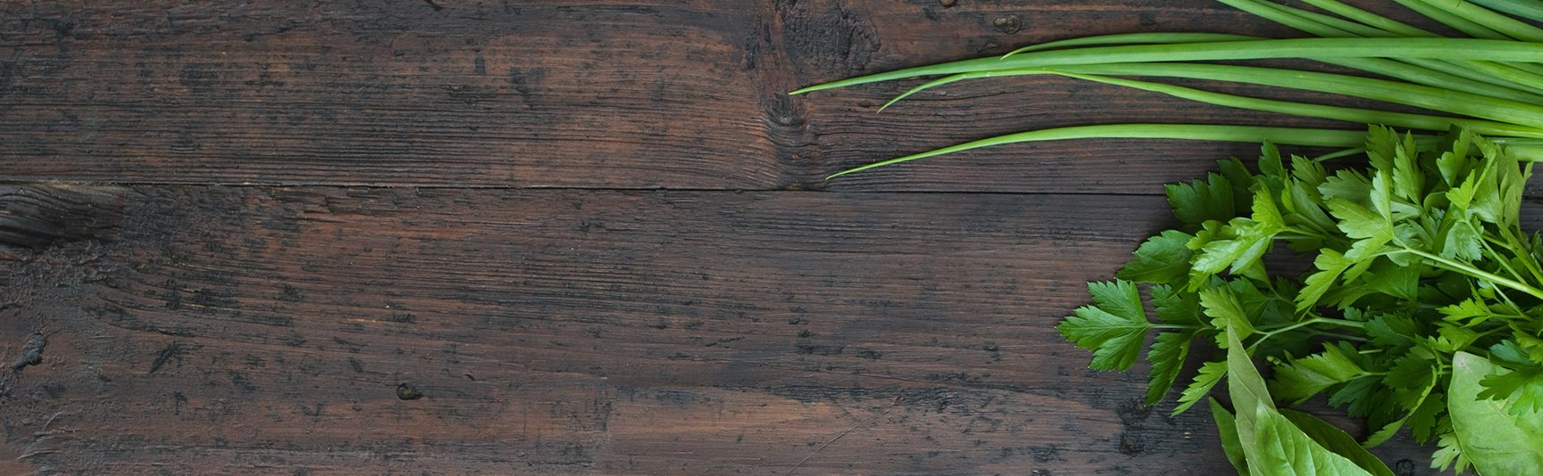 Fresh herbs laid on a dark rustic wooden table